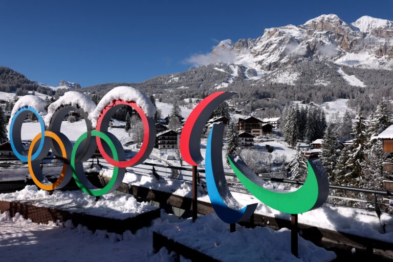 Official logo of the Milano Cortina 2026 Winter Olympics with the Italian Alps in the background.