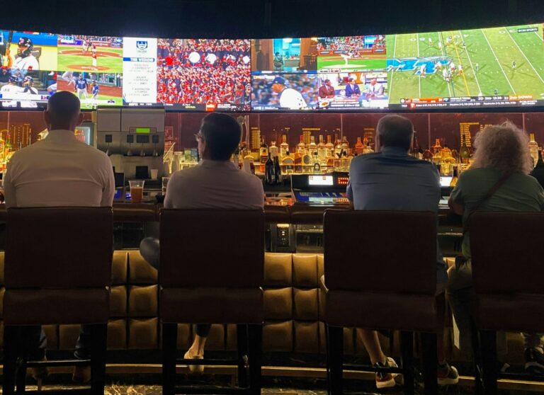 Sports fan watching a match on TV while using a smartphone